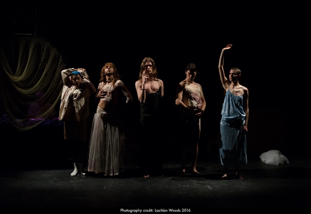 A darkened image of five performers standing inn different poses.